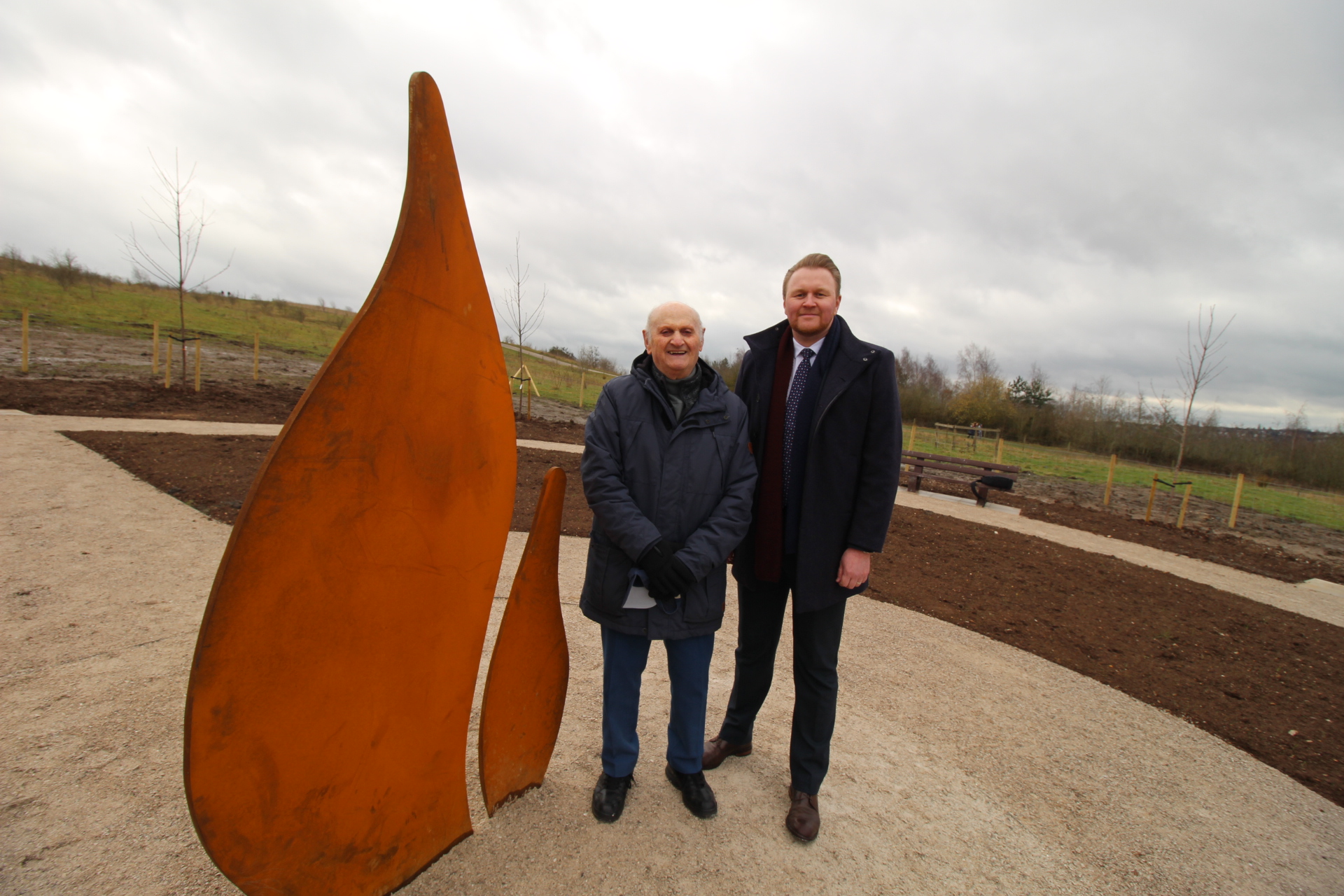 Cllr Payne and Simon Winston stood next in the garden next to the steel flame